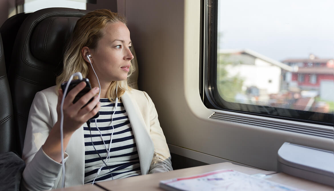 Woman on train listening to CUES podcasts
