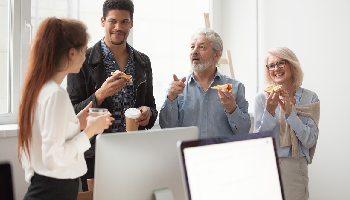 group of mixed age executives talking while eating pizza