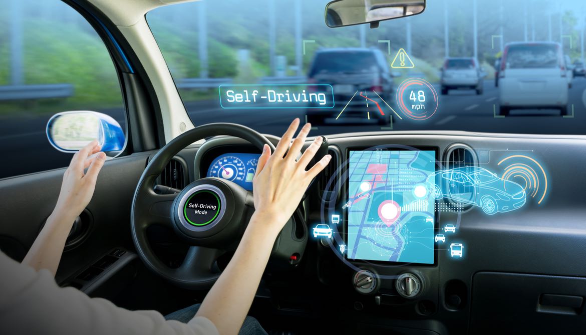 woman at steering wheel with self driving mode on her car's screen