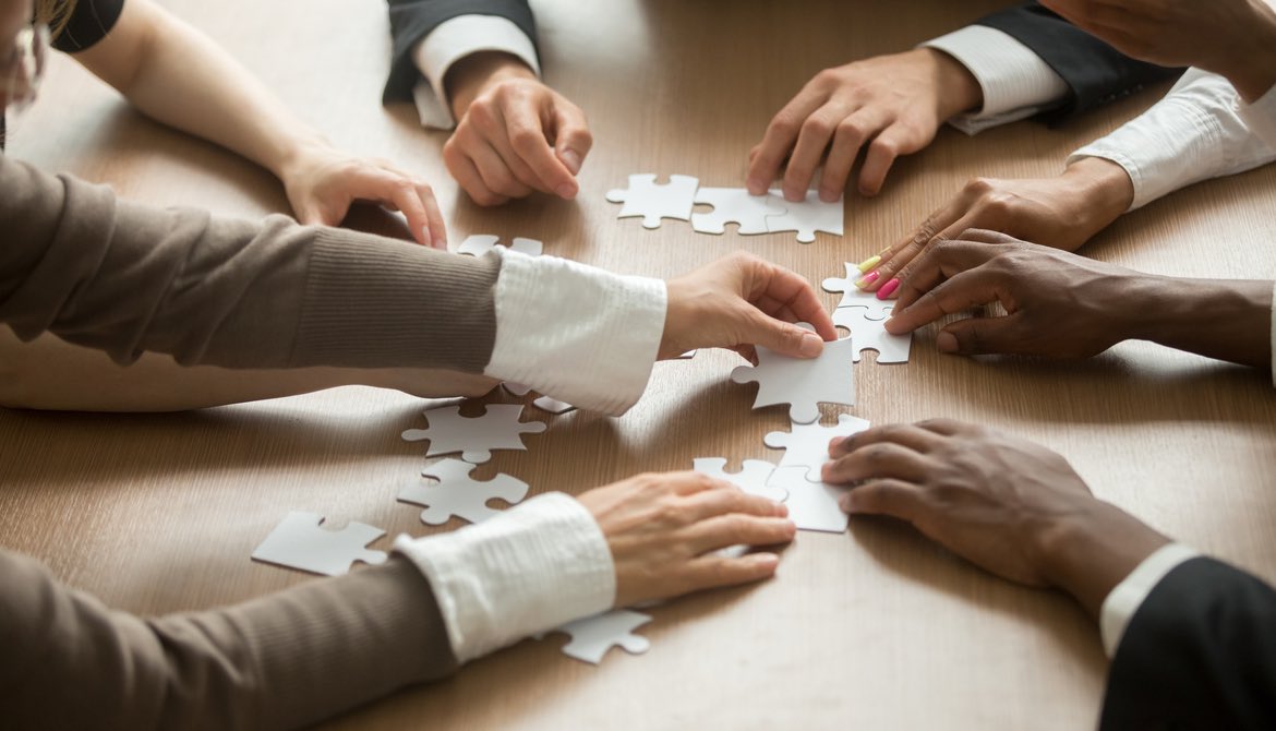 diverse group of business people putting together a puzzle on a table