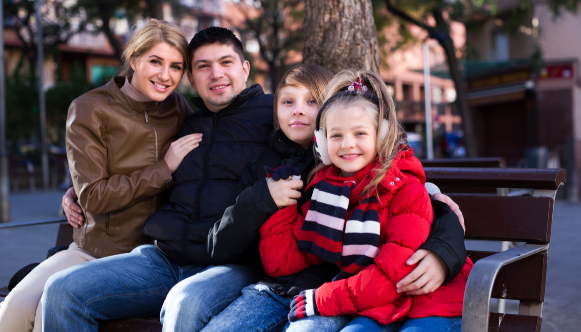 Average family with two kids sitting on bench outdoors
