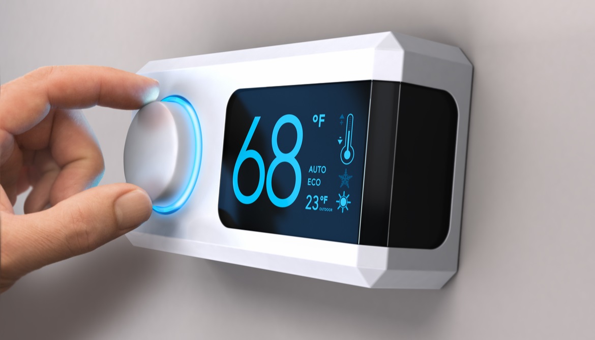 hand adjusting a digital thermostat set to 68 degrees
