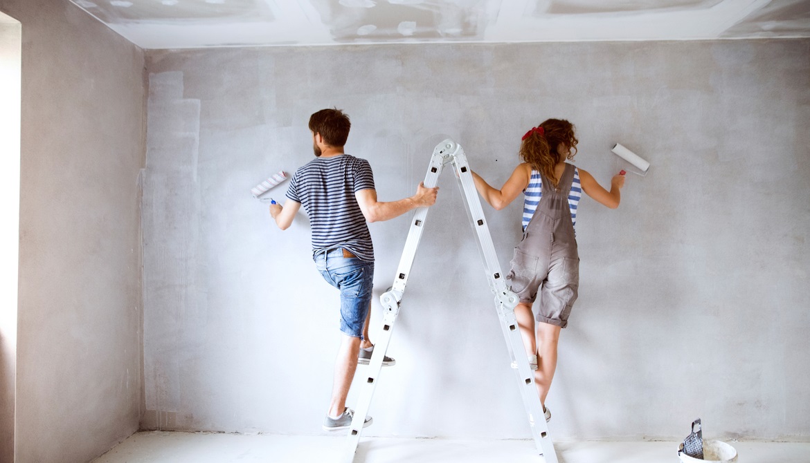 young couple on a ladder painting walls of new house