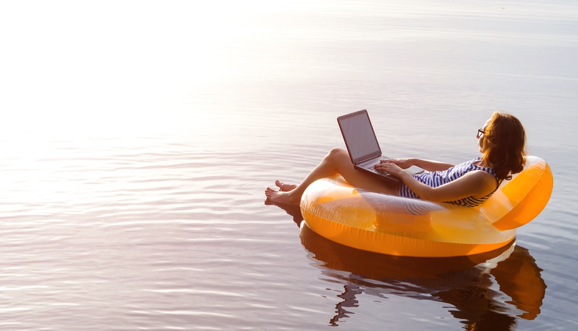 female workaholic using laptop while floating on a lake