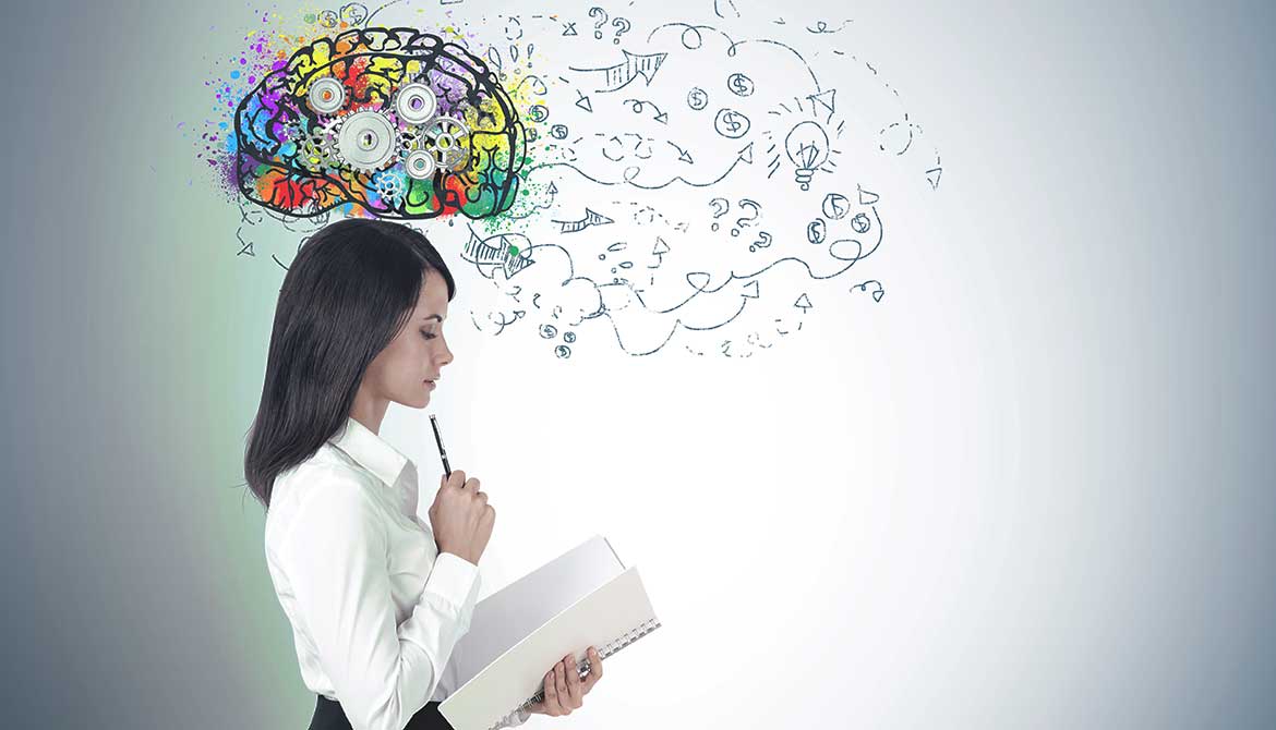 business woman studies a notebook with a colorful brain full of gears above her head