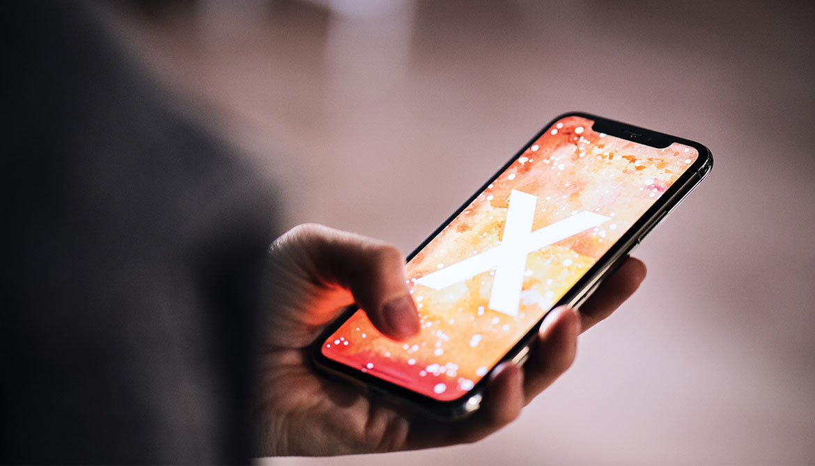 person holding smartphone with glowing X on screen