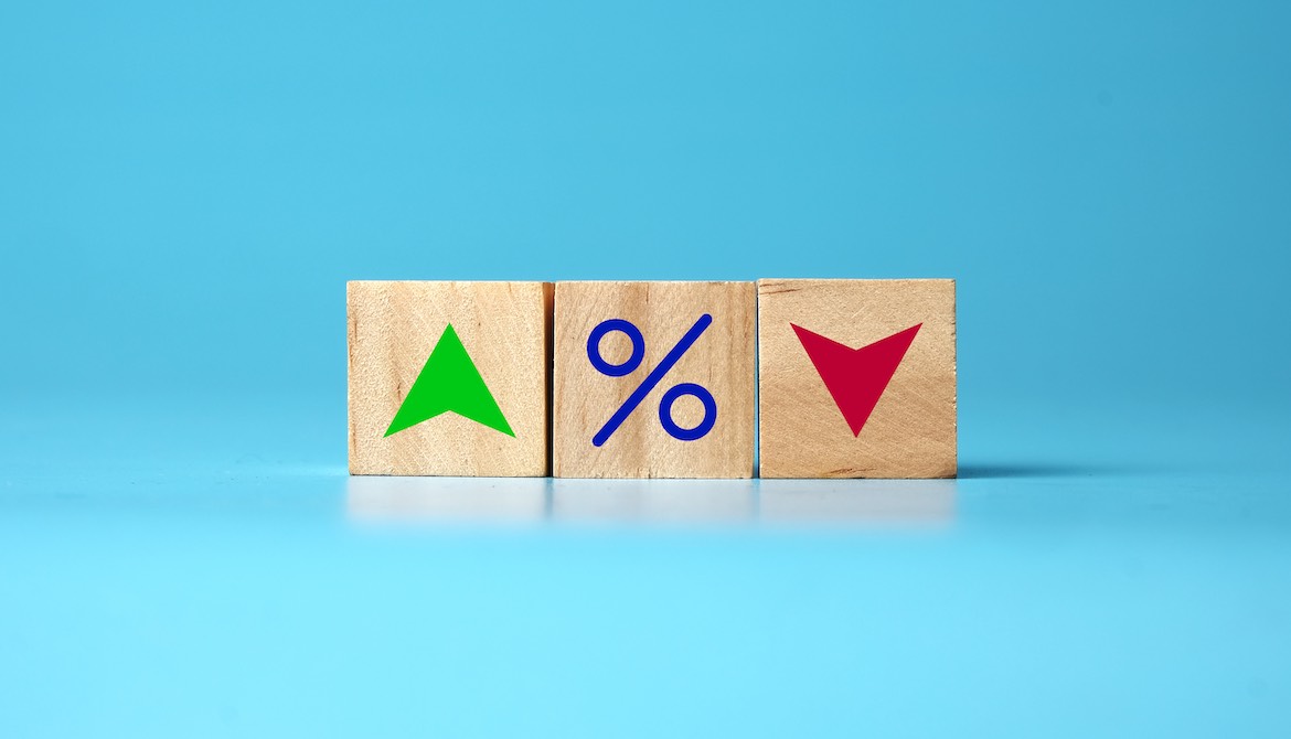 wooden blocks with a green up arrow a percent sign and a red down arrow representing interest rates