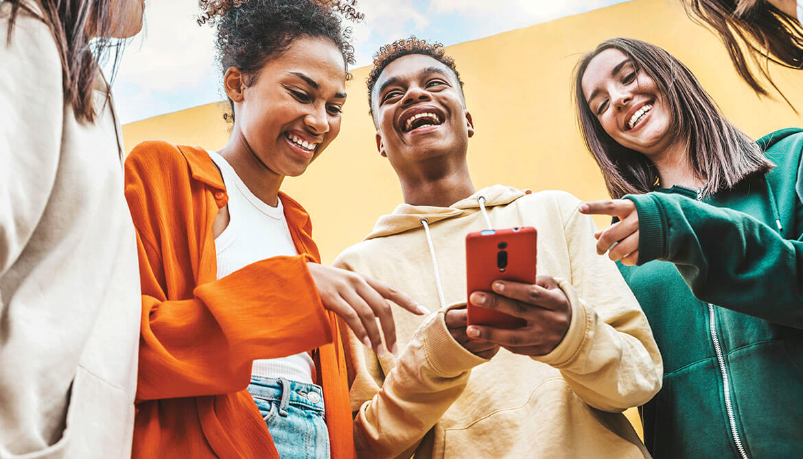 Group of smiling laughing young people looking at smartphone