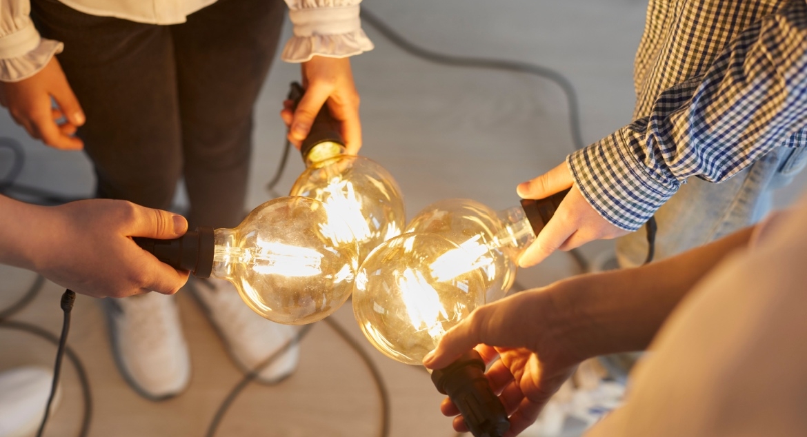 Close up of bright light bulb in the hands of different people