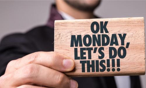 man holds sign that says Ok Monday Lets Do This