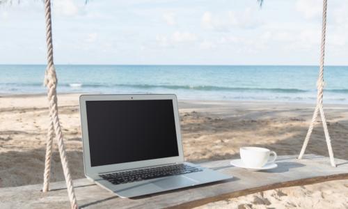 laptop and coffee cup on a swing by the beach