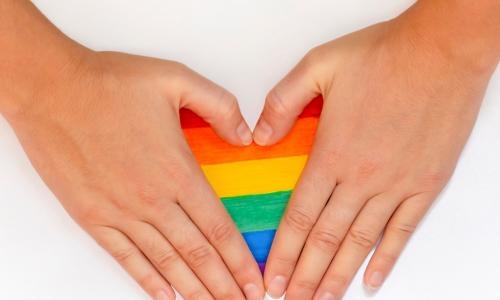 hands forming a heart over a rainbow