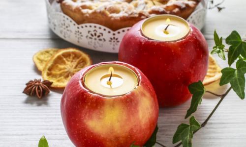 tea candles set into hollowed out apples sitting on a white wood table in front of a pie