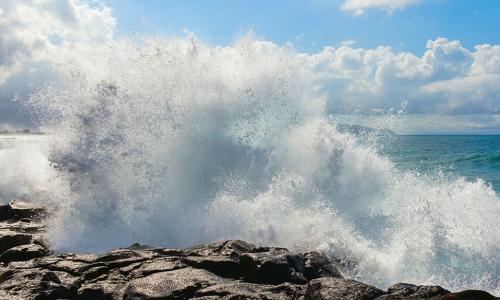 big wave crashing against rocks and spraying high into the air