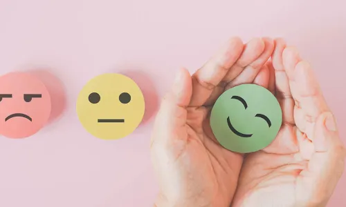 hands holding paper circle green smiley face next to red angry and yellow neutral faces