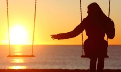 empty swing woman on swing at sunset