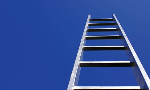 view from below of a ladder climbing high into blue sky