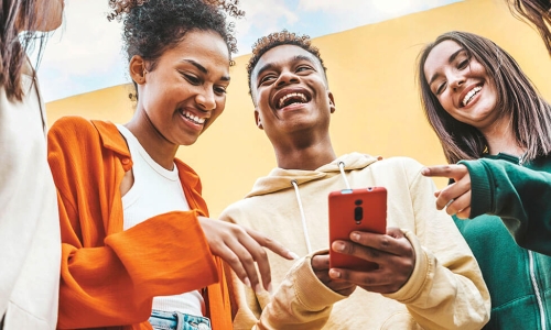 Group of smiling laughing young people looking at smartphone