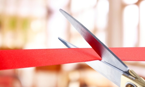 large scissors cutting a red ribbon