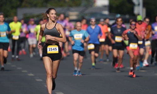A female runner is ahead of the pack during a running race