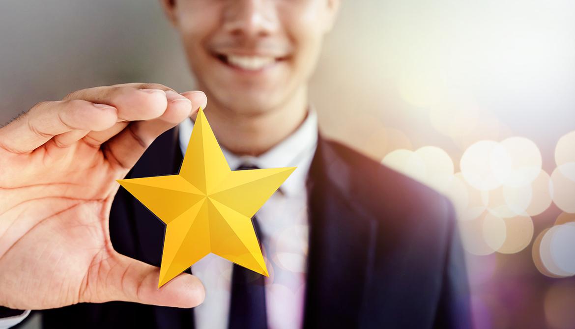 Happy Businessman in black suit Smiling and Showing a Golden Star in Hand