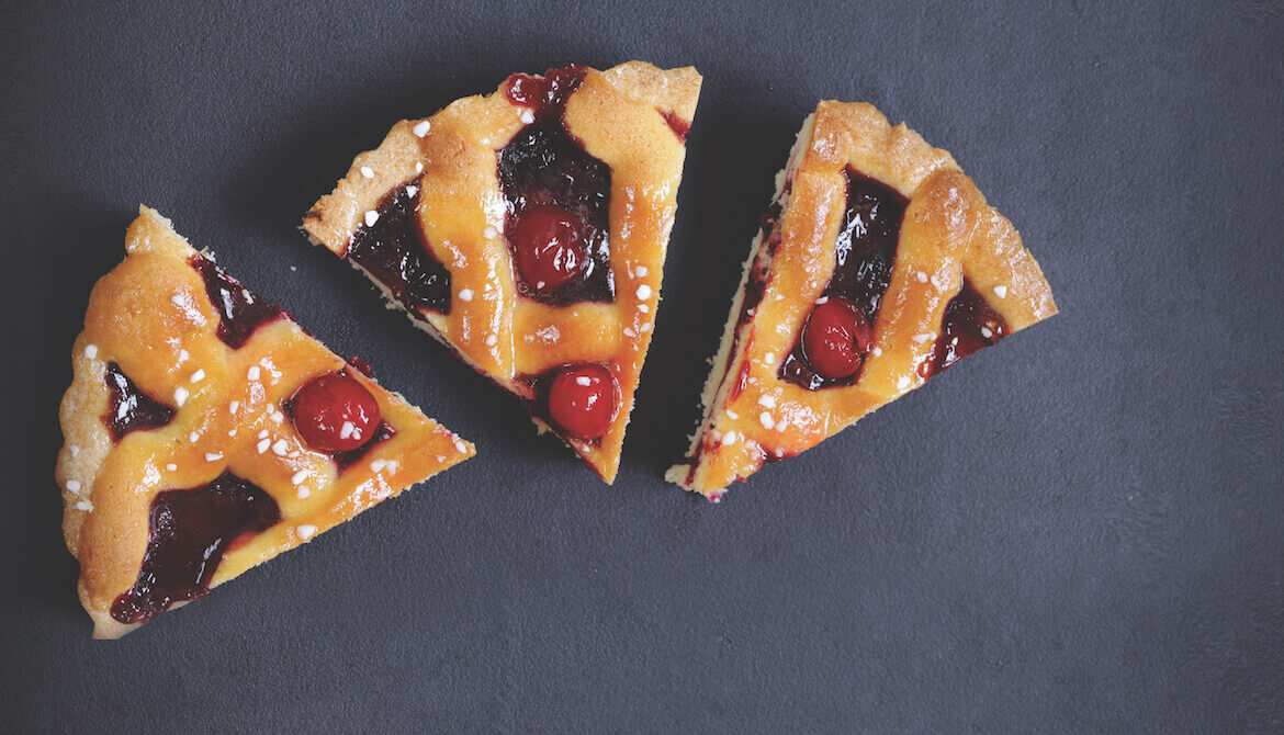 three pieces of cherry pie on a gray backdrop, one slightly smaller than the other two