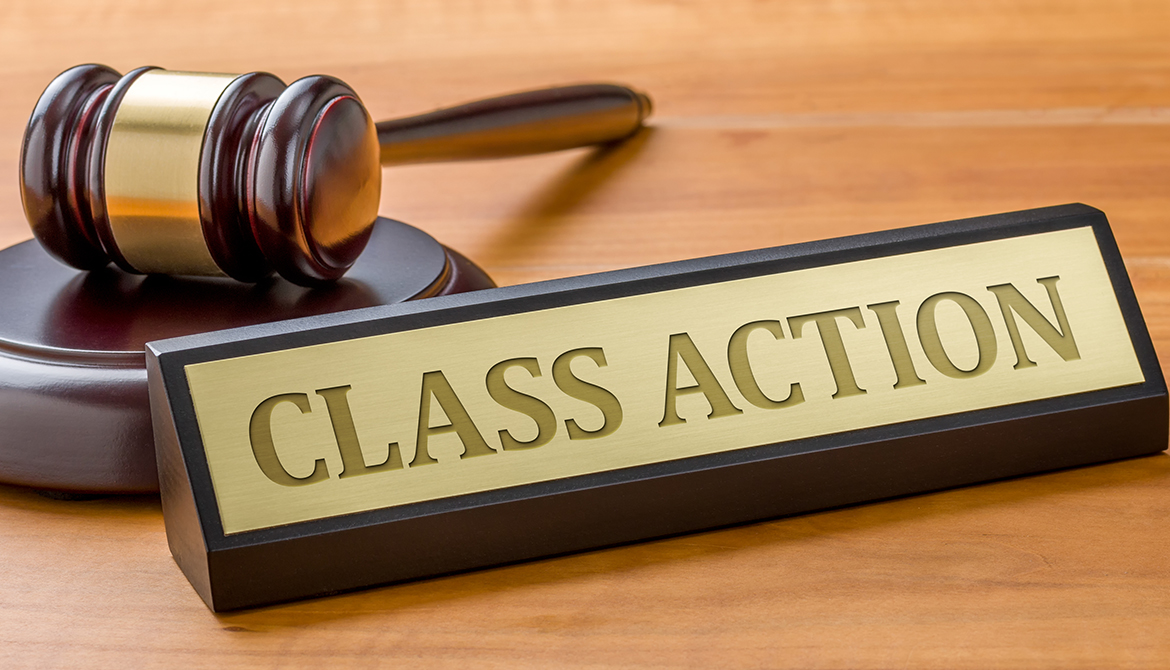 Gavel laying on a desk next to a brass plaque that reads class action