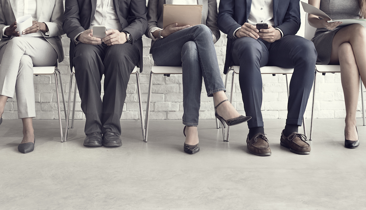 Five job candidates waiting on chairs without faces showing to know their age and race