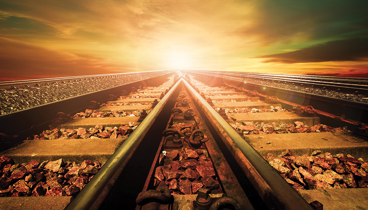 train tracks converging in front of a sunset sky
