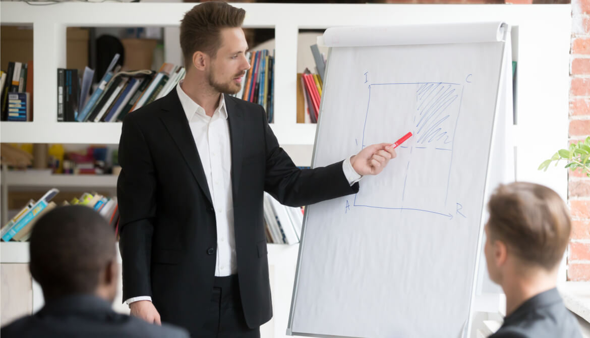 man stands at a flipboard in a meeting