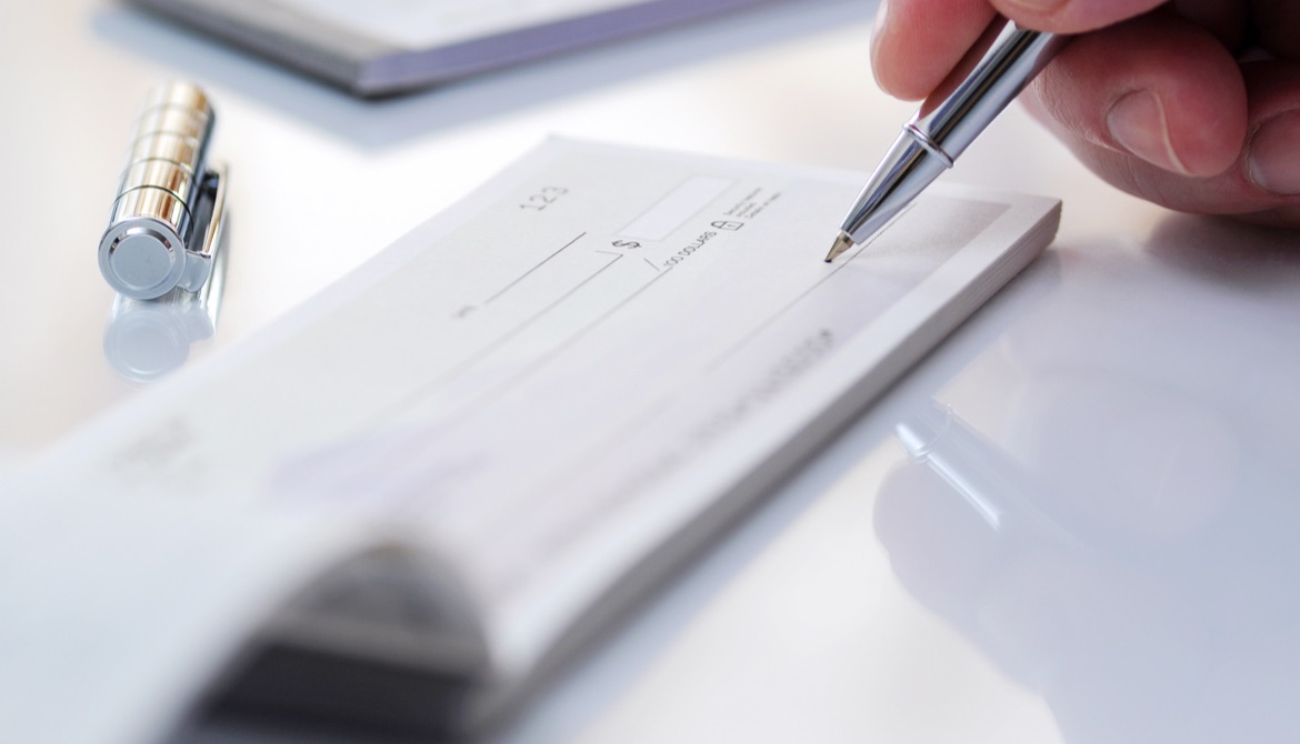 person writing a check with a silver pen