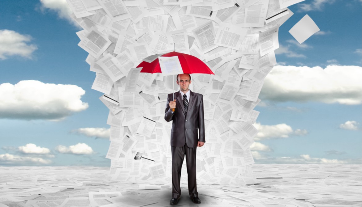 businessman holding umbrella under a deluge of documents