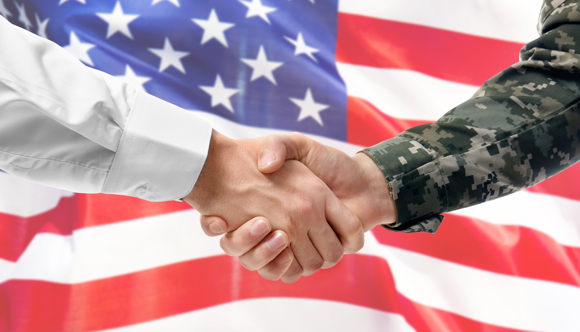 civilian and military arms shake hands in front of a U.S. flag