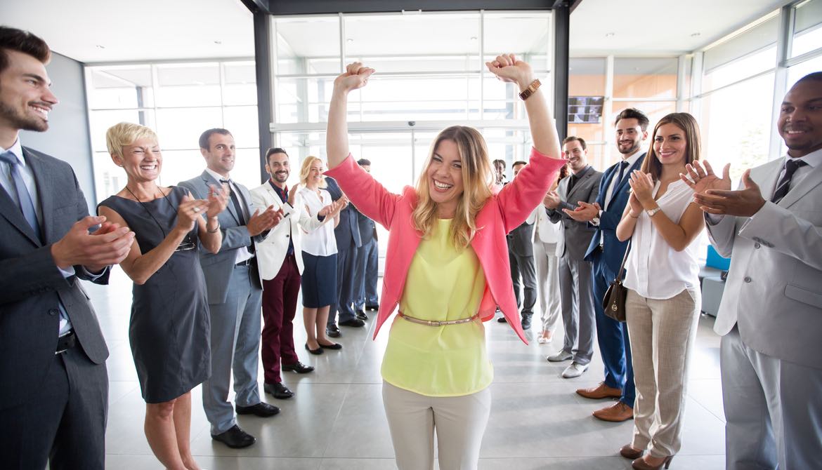 woman walking through a cheering hall of colleagues