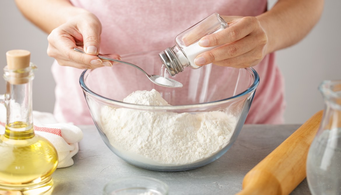 woman adding salt to dough