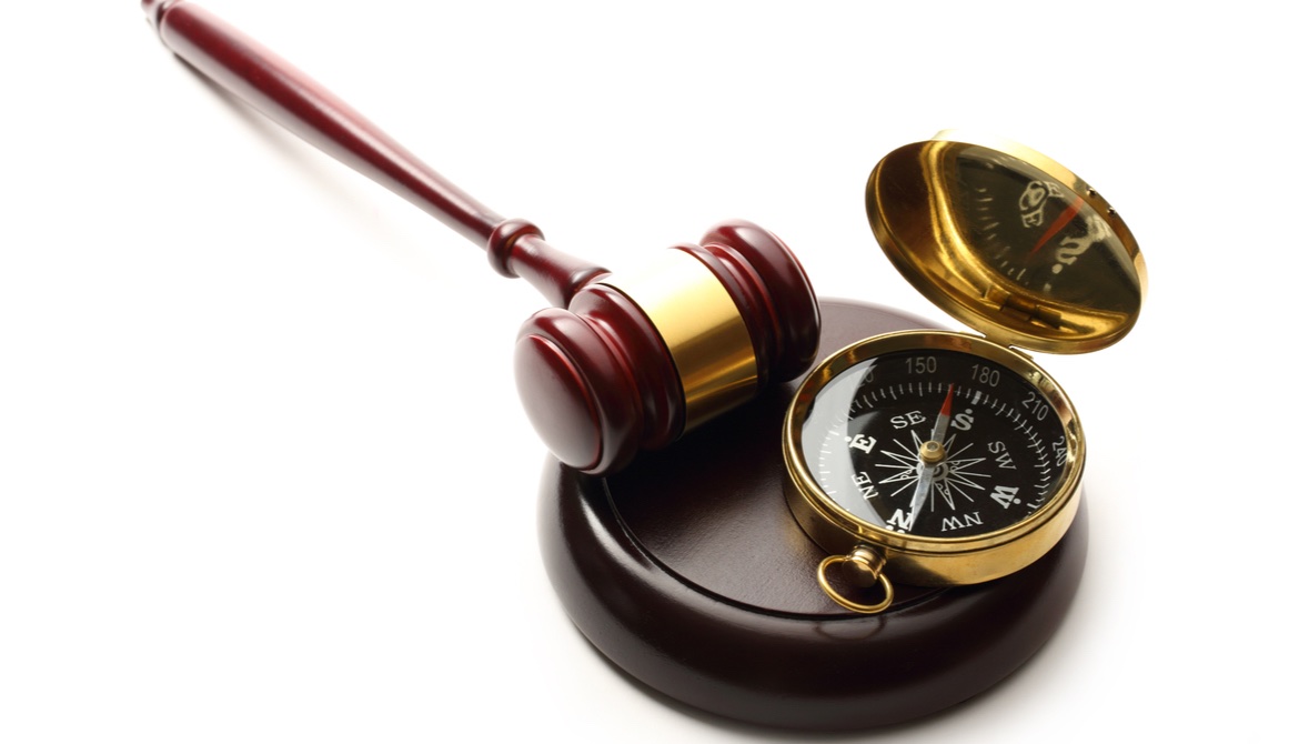 gavel lying next to a brass compass