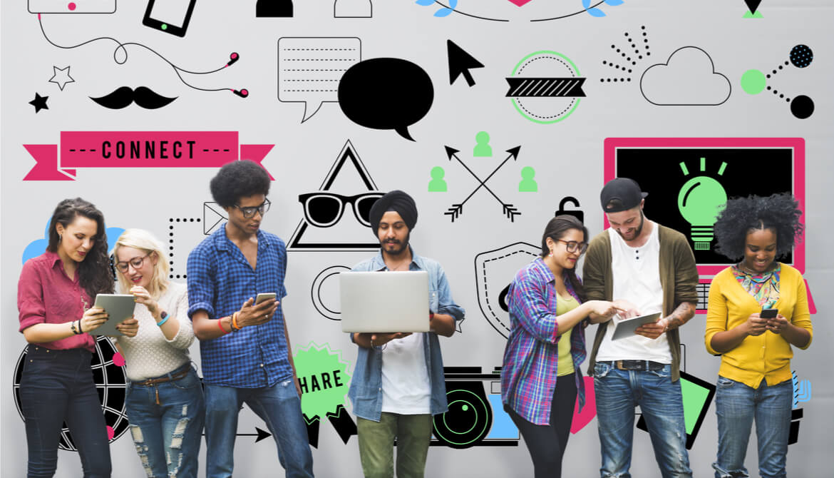 Group of Generation Z members using mobile devices standing in front of a wall of illustrations depicting social media trends and technology