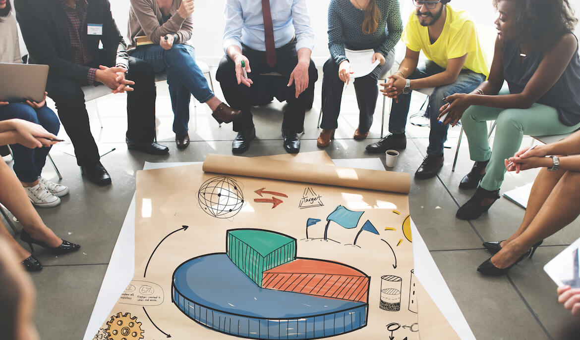 group of professional workers sitting in a circle looking at a colorful graph on the floor