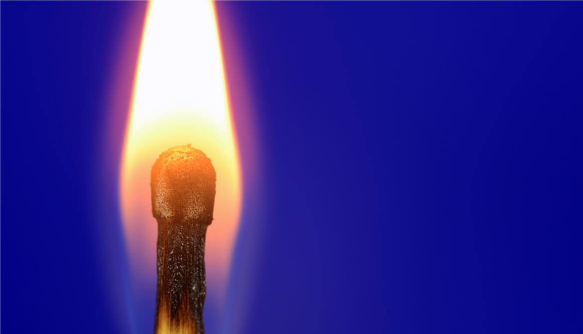 A burning match on a blue background