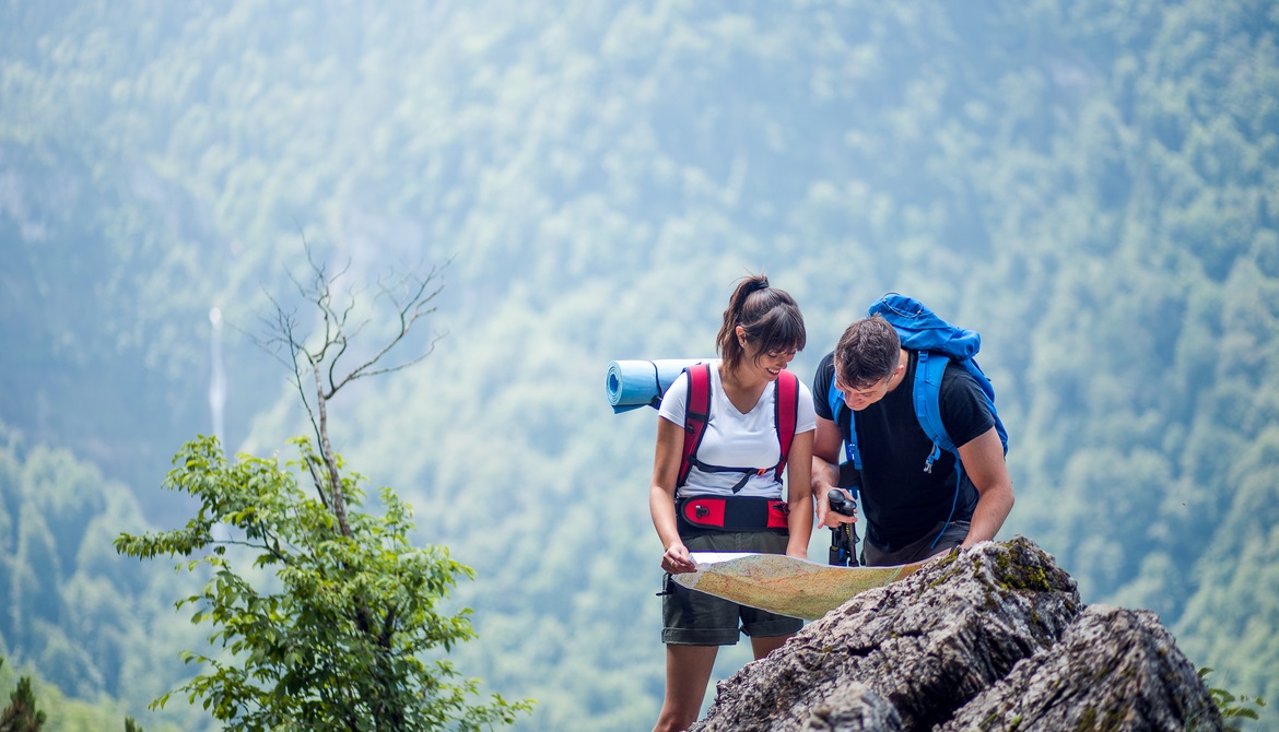 young male and female hikers using a map to navigate