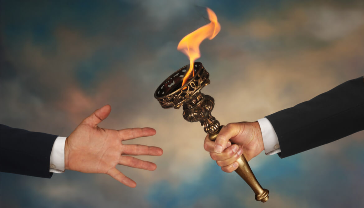 two businessmen passing a torch