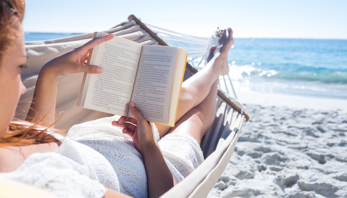 woman reading on the beach in a hammock