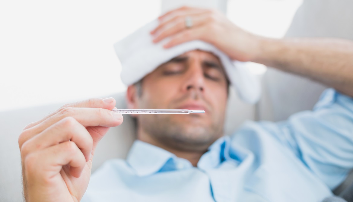 sick businessman looking at thermometer