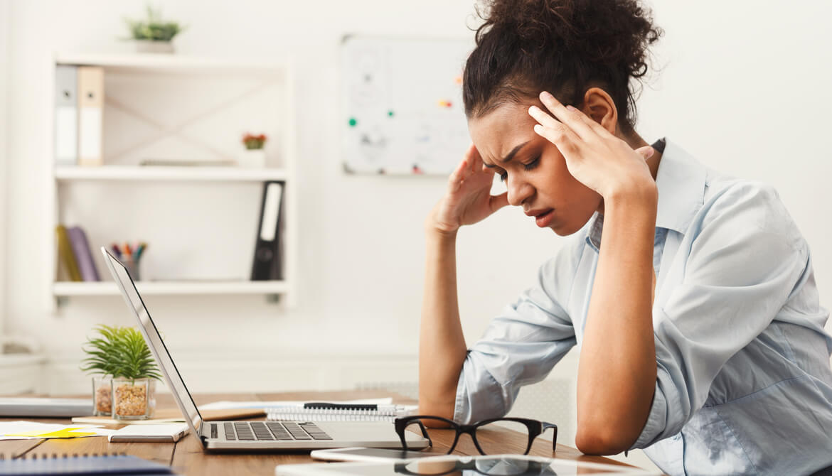 Tired African-American business woman with headache at office