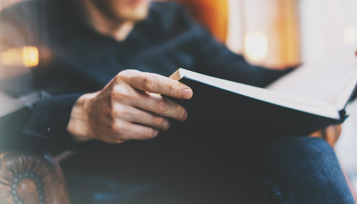 man reading book in leather arm chair