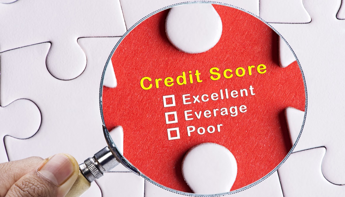 a magnifying glass focusing on the words credit score on a puzzle piece in a larger white puzzle