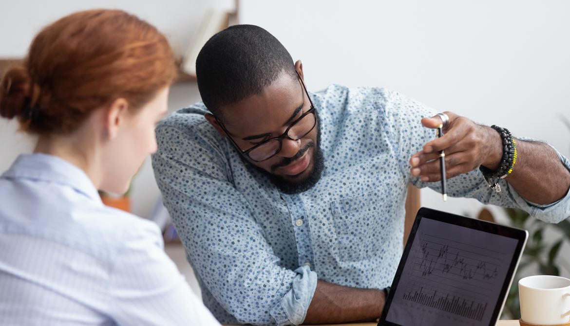 African-American man teaching a red-headed women over a computer