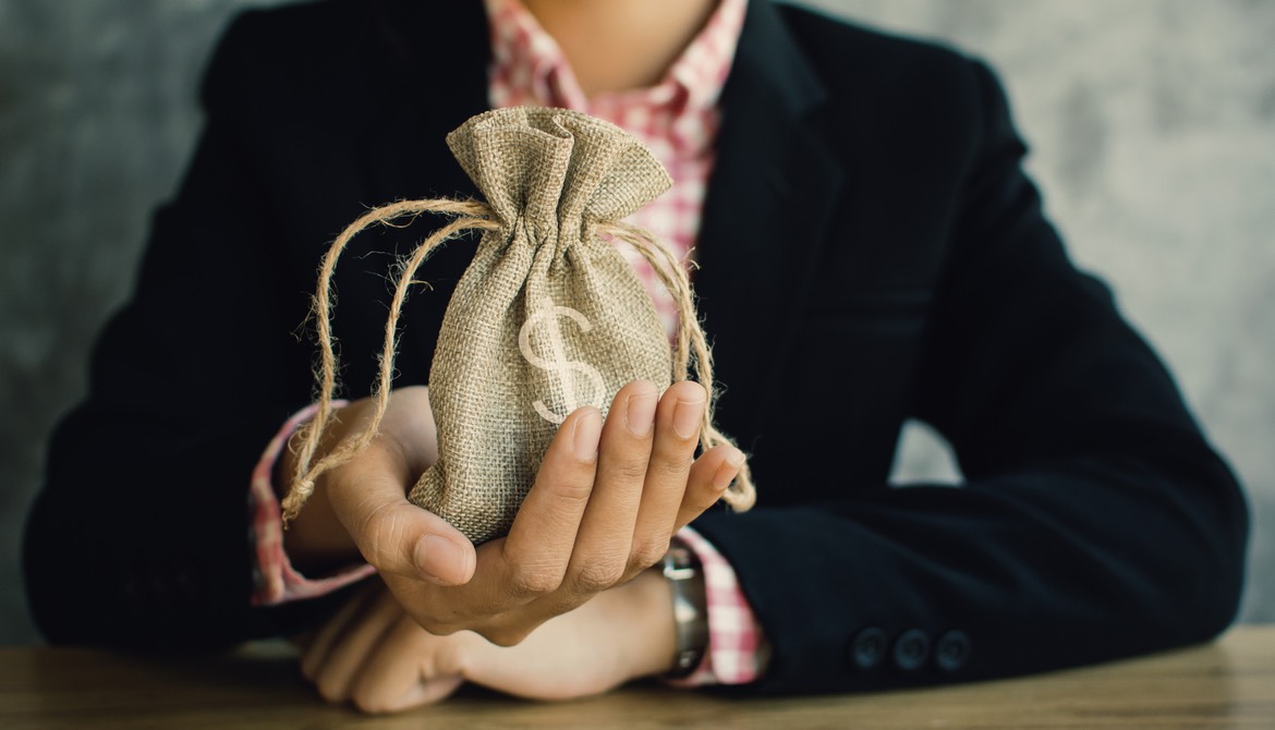 female executive with burlap bag with money symbol in her hand