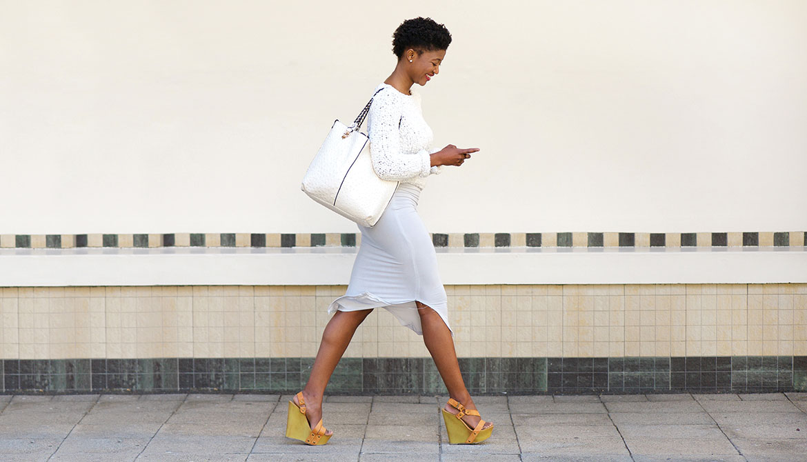 happy young woman walking and texting