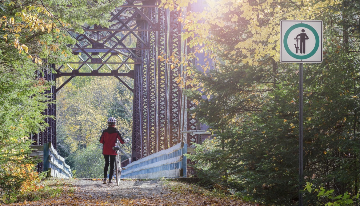 female bicyclist follows the rules by walking her bike across a bridge